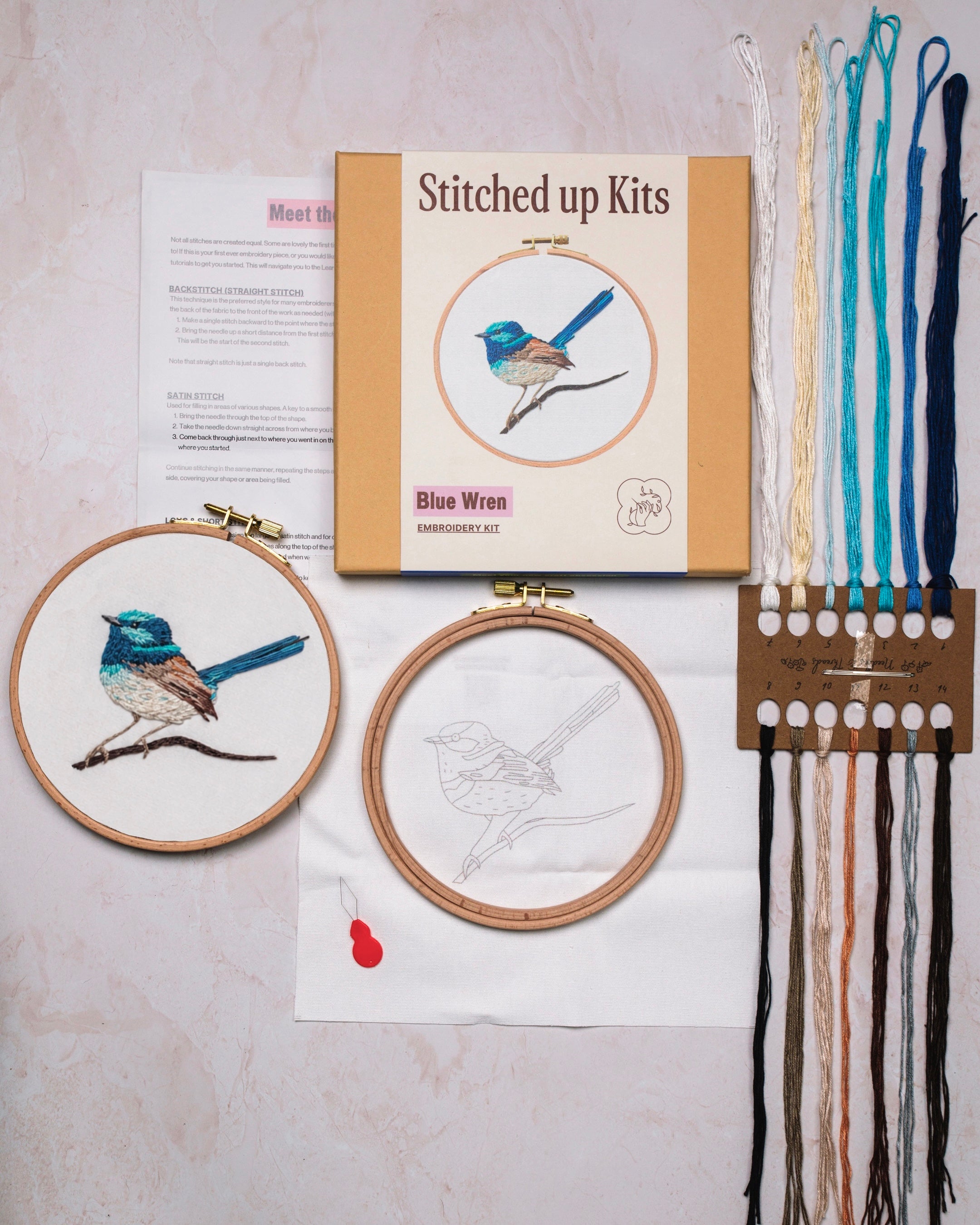Embroidery kit with completed and in-progress embroidery pieces on a light surface.