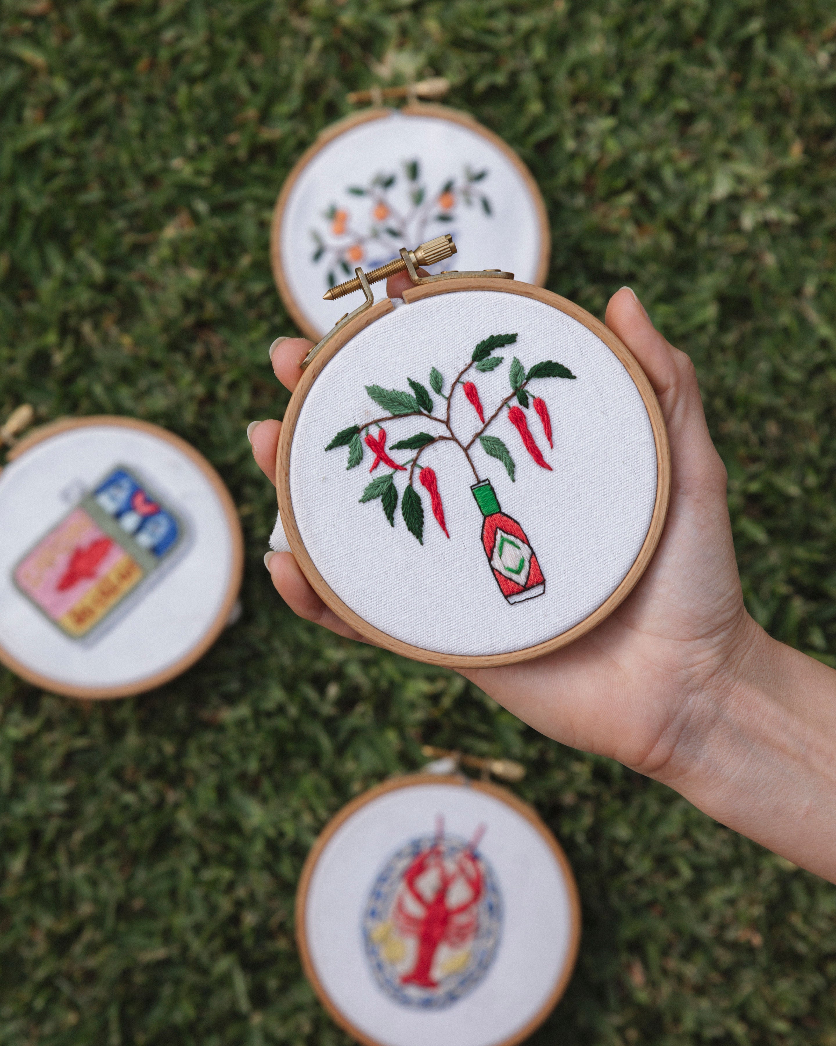All The Mini Italian Collection embroidery hoops featuring Tabasco sauce, chili peppers, and Italian-inspired designs on white fabric