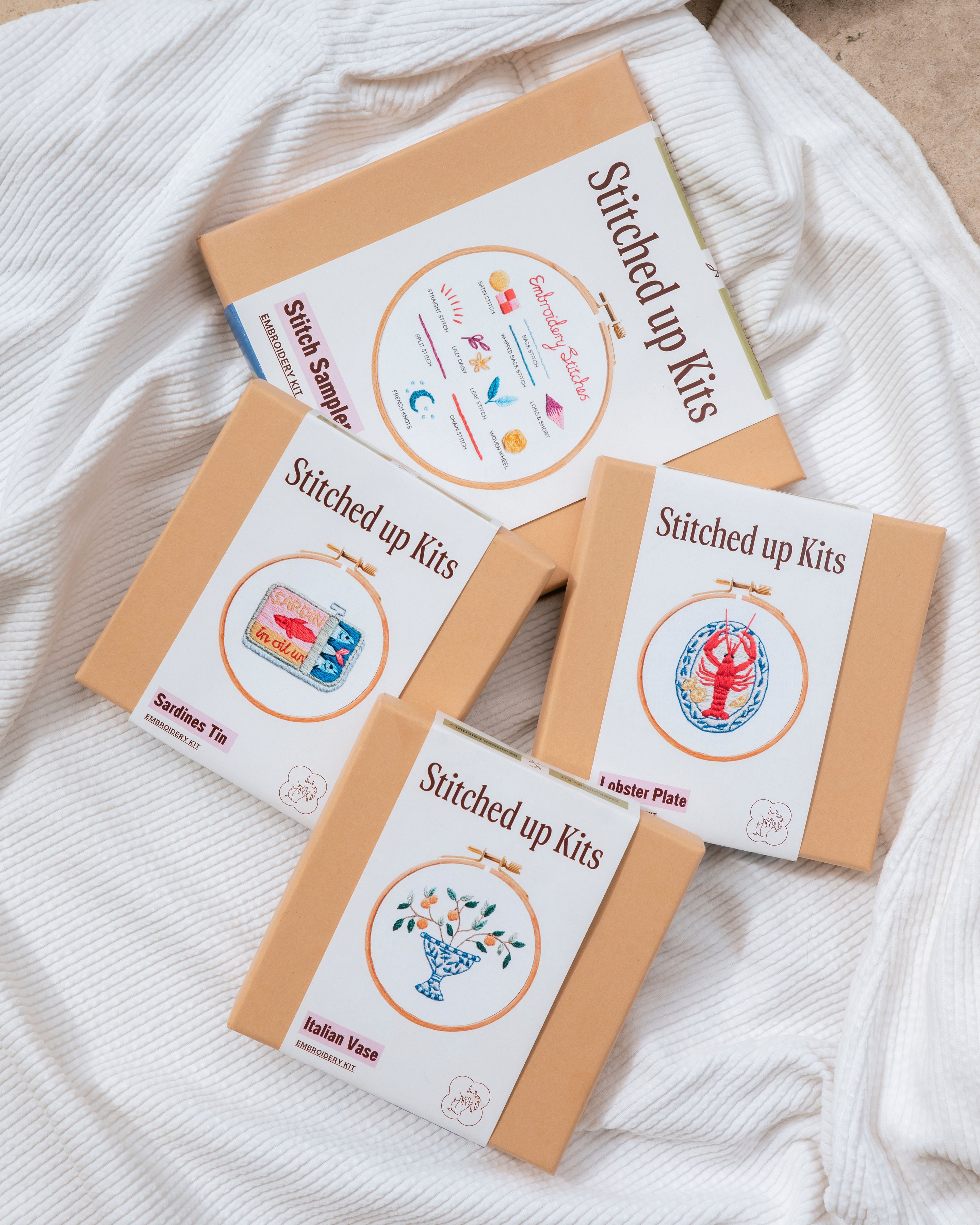 All The Food Minis embroidery kits with illustrated lobster, sardines, and floral vase designs in modern packaging.