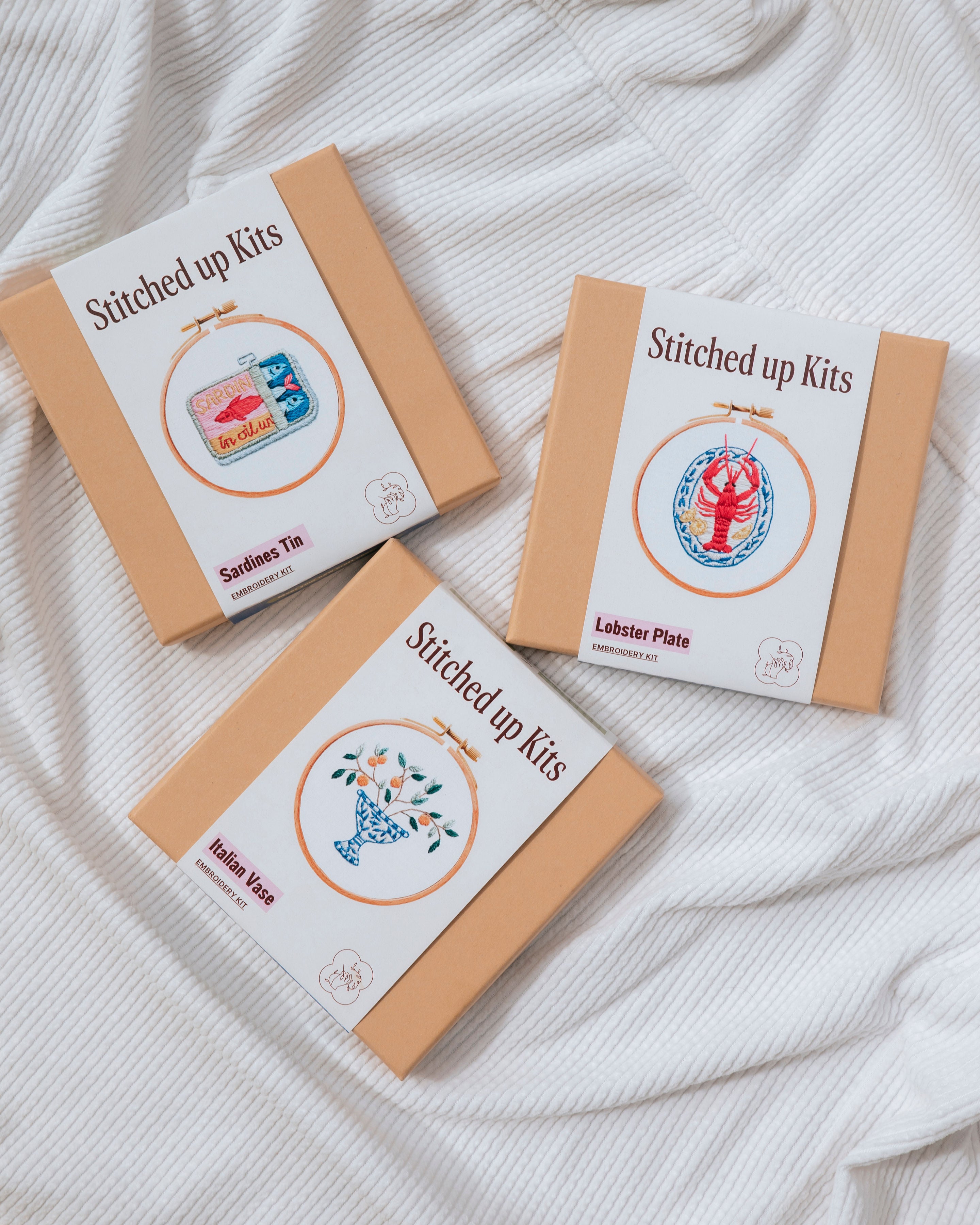 Girls Stitch Night Bundle showing three modern embroidery kits with seafood and floral designs in tan boxes on white fabric