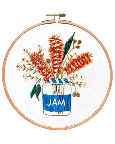 Completed embroidery piece in a wooden hoop on a white background - Blue Jam Jar, with Australian Bottlebush flowers and gum leaves sticking out of the jar.